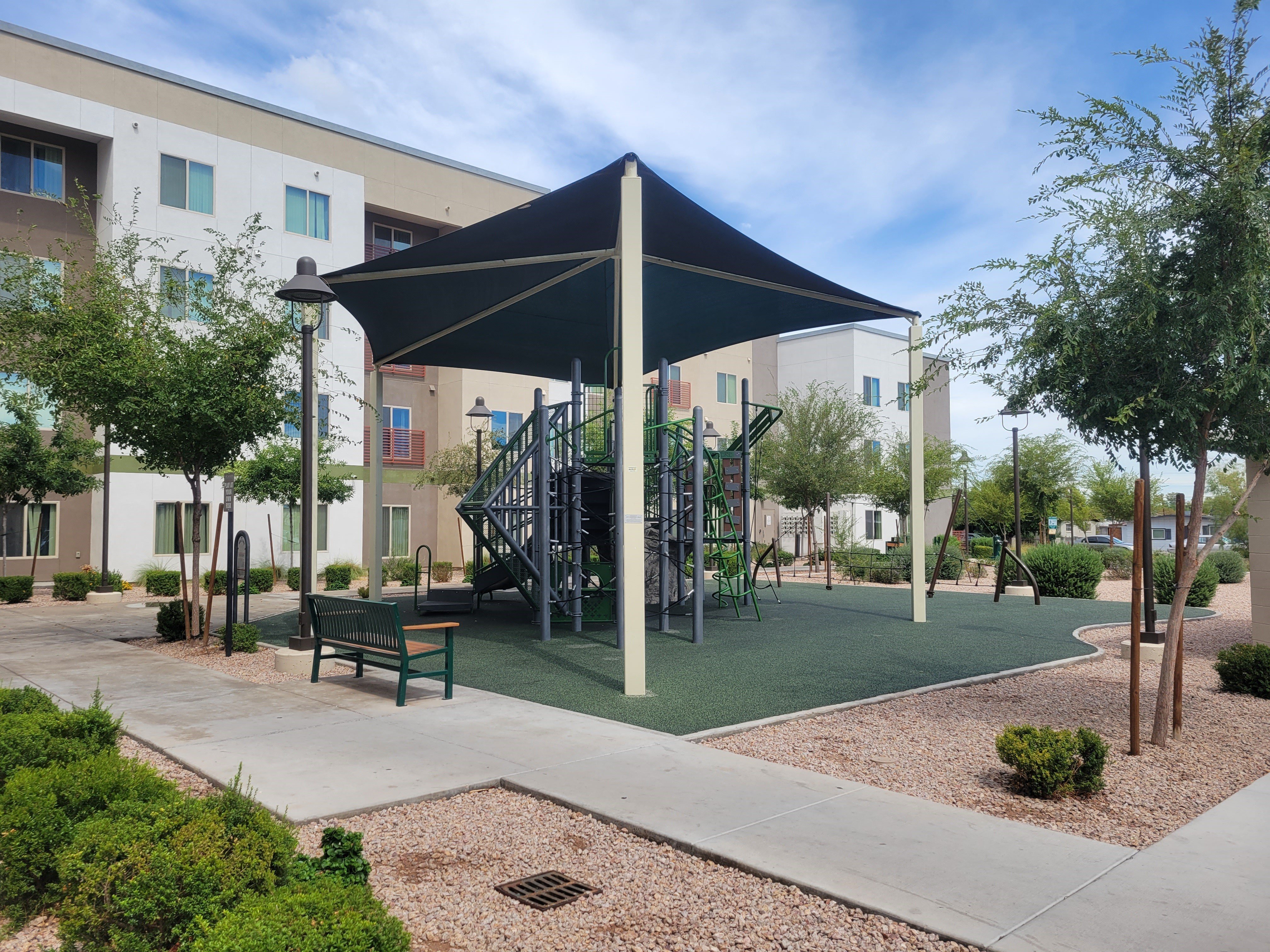 a playground with a swing set in front of an apartment building